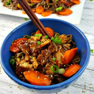 Close up of Slow Cooker Honey Chicken in a blue bowl with chop sticks.