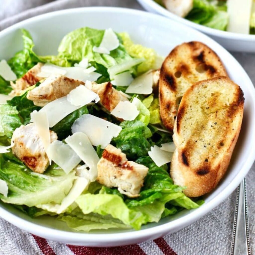 Large bowl of Chicken Caesar Salad with garlic bread.