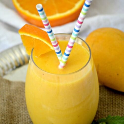 Orange Mango Smoothie in a small glass with two straws.