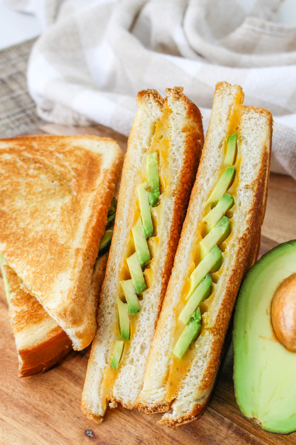 Avocado Grilled Cheese sandwich next to an avocado half.