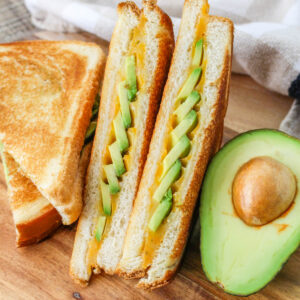 Avocado Grilled Cheese sandwich next to an avocado half.