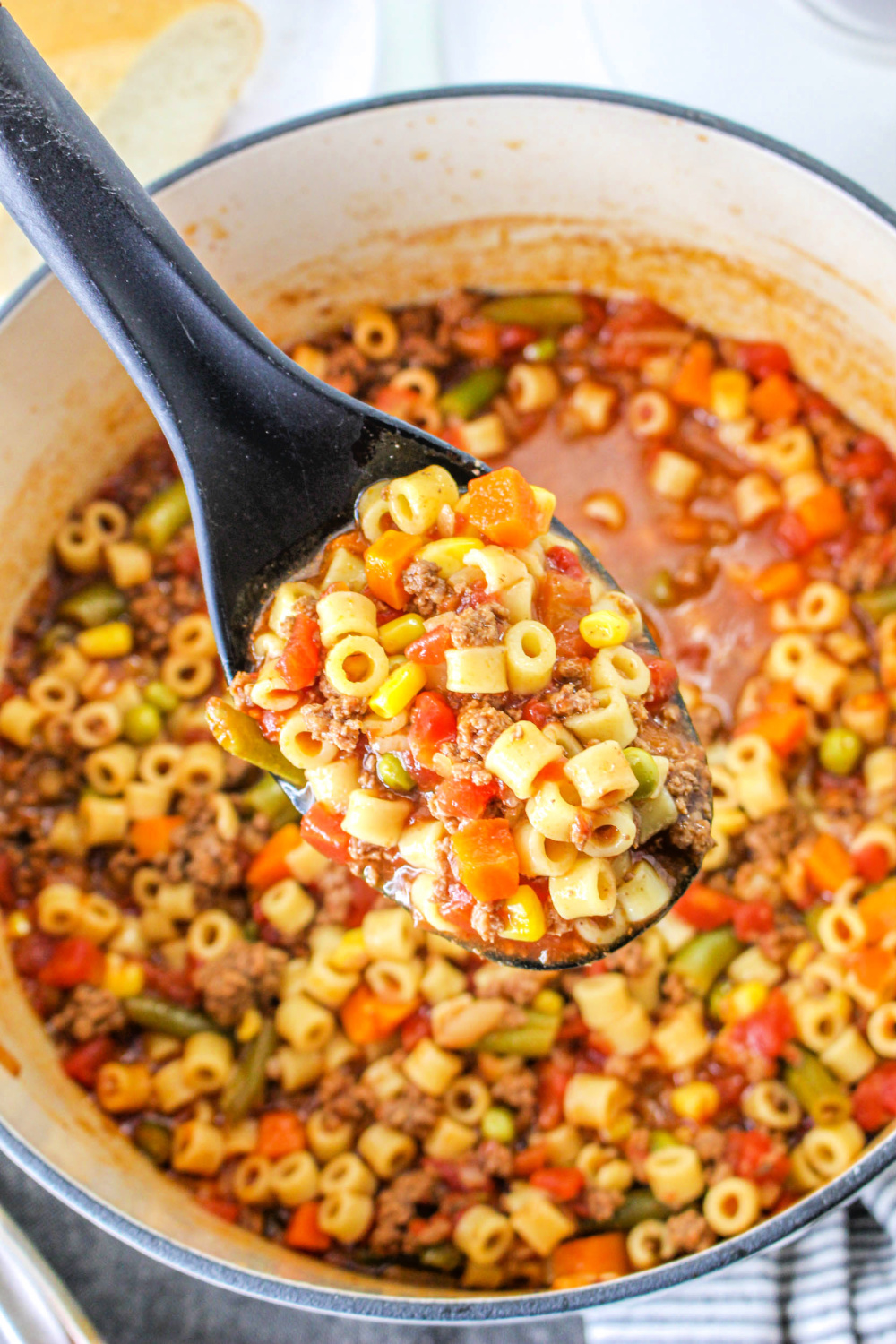 A full serving spoon above a pot of Busy Day Soup.