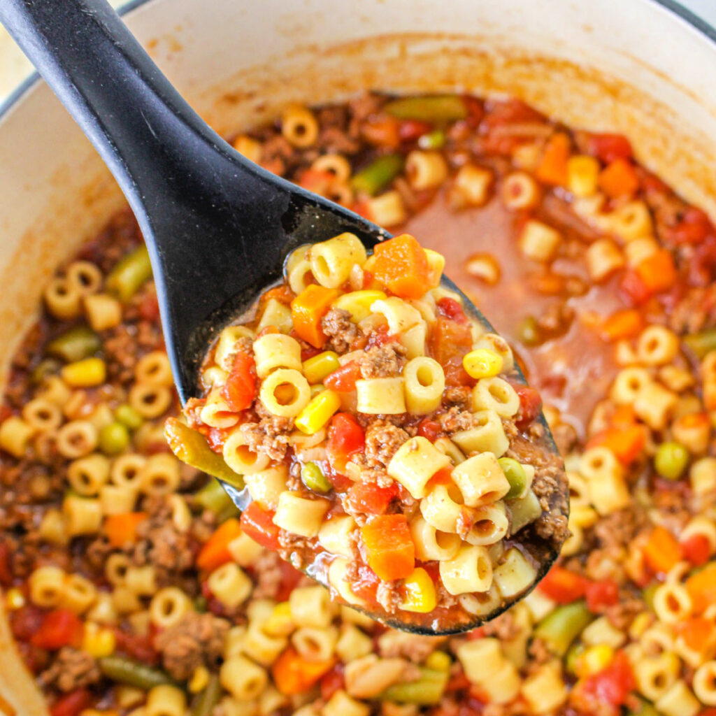 Close up of a full serving spoon above a pot of Busy Day Soup.
