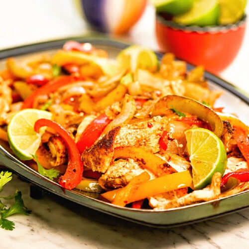 Close up of Fajita Sheet Pan Chicken Dinner with peppers and limes.
