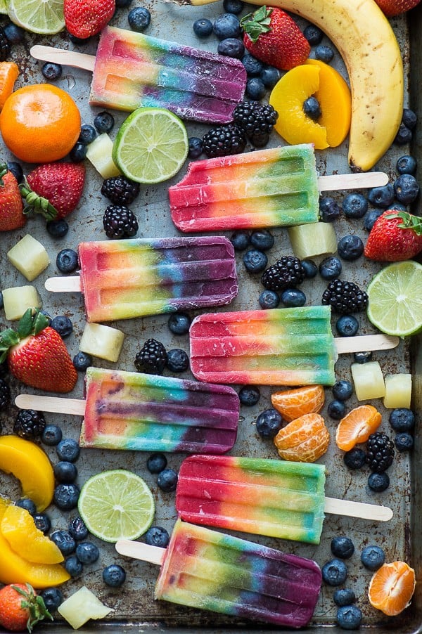 Tio doiwb view of Rainbow Popsicles on a tray with fresh fruit.