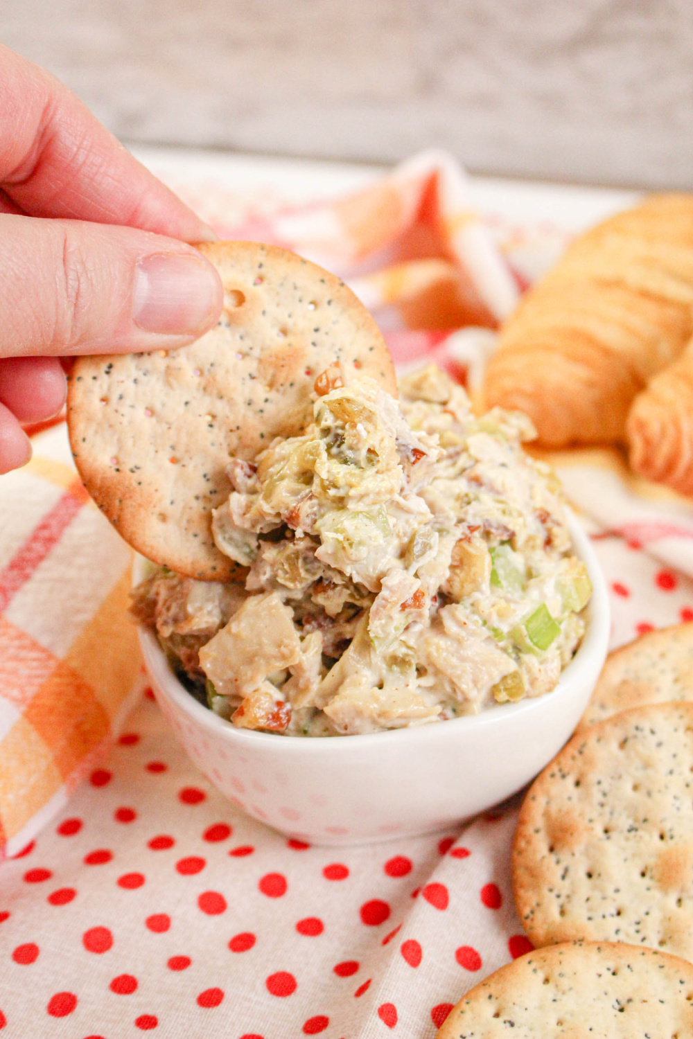 Hand scooping Rotisserie Chicken Salad with a cracker.