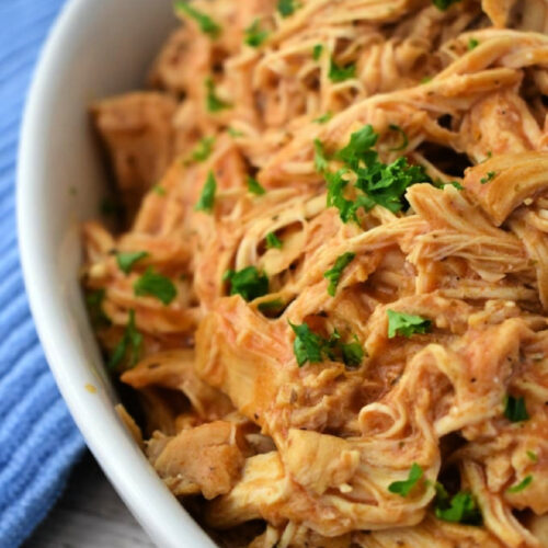 Close up of Crockpot Buffalo Chicken garnished with parsley in a bowl.