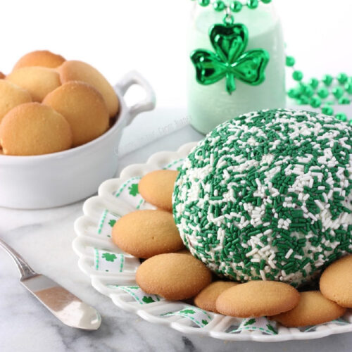 Cream Cheese Ball with green and white sprinkles on a serving platter with vanilla wafer cookies.