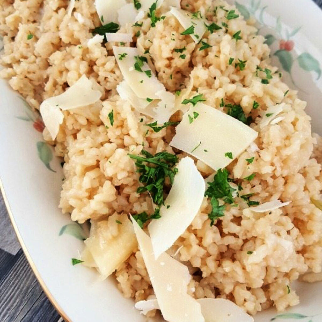 Close up of Rice Cooker Parmesan Risotto Recipe with parsley and shaved parmesan cheese.