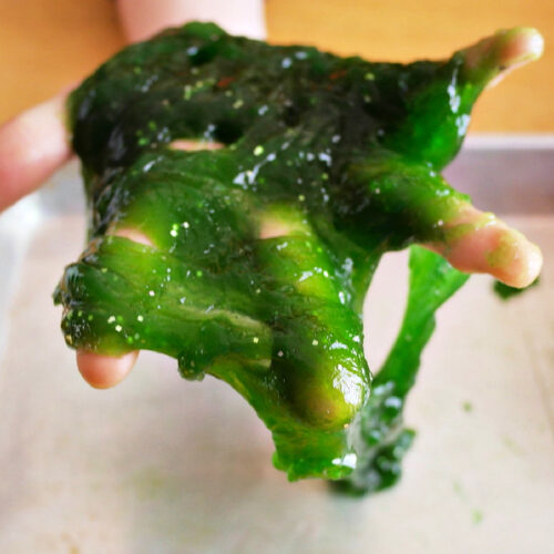 A child's hand holding green 2-Ingredient Oobleck.