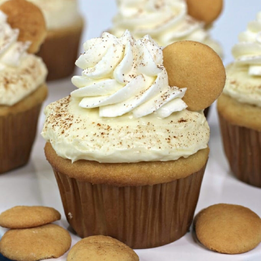 Close up of Banana Pudding Cupcake with whipped cream and a nilla wafer on top.
