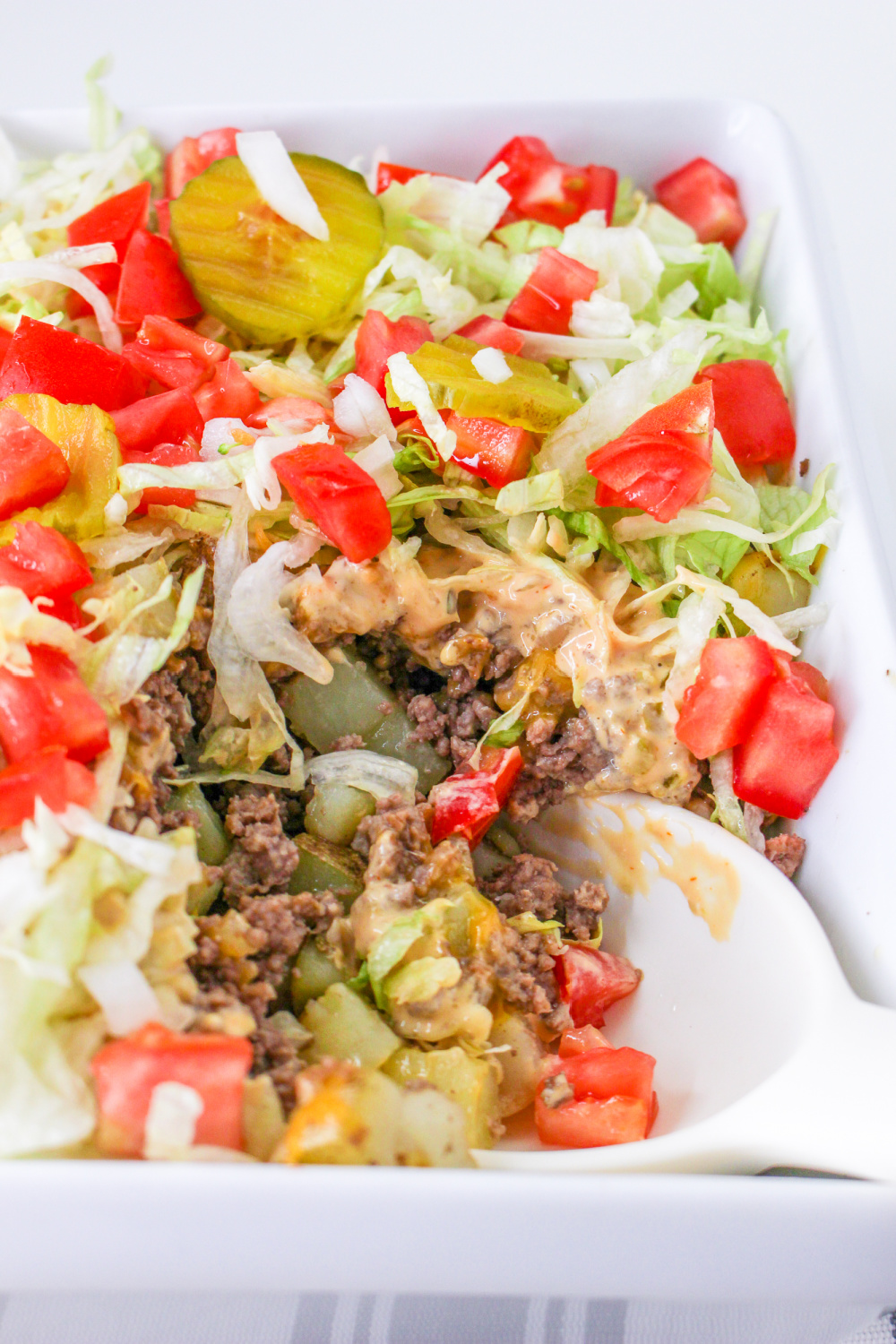 Big Mac Casserole in a baking dish with a spoon.
