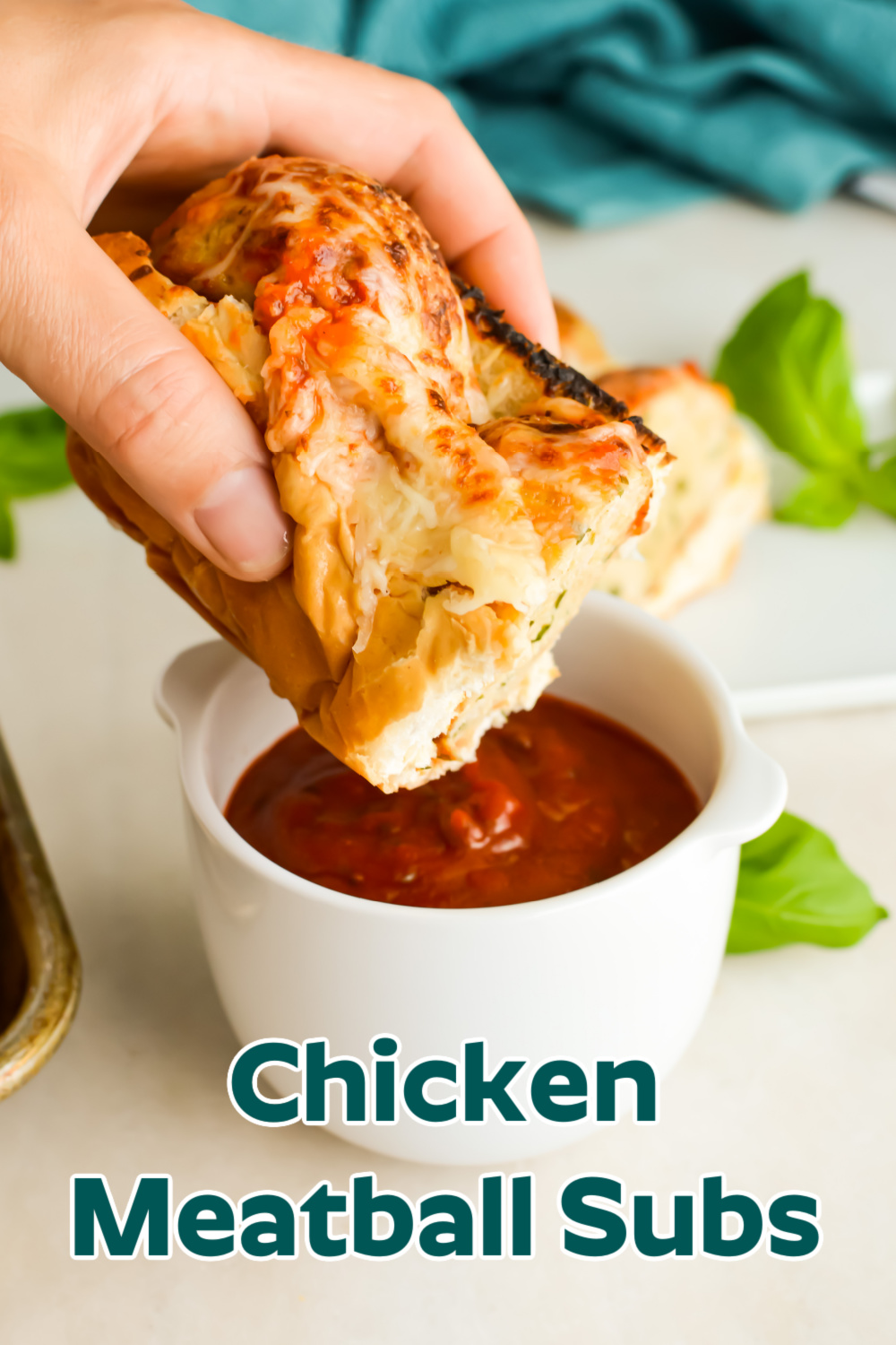 Hand dipping a Chicken Meatball Sub into tomato sauce.