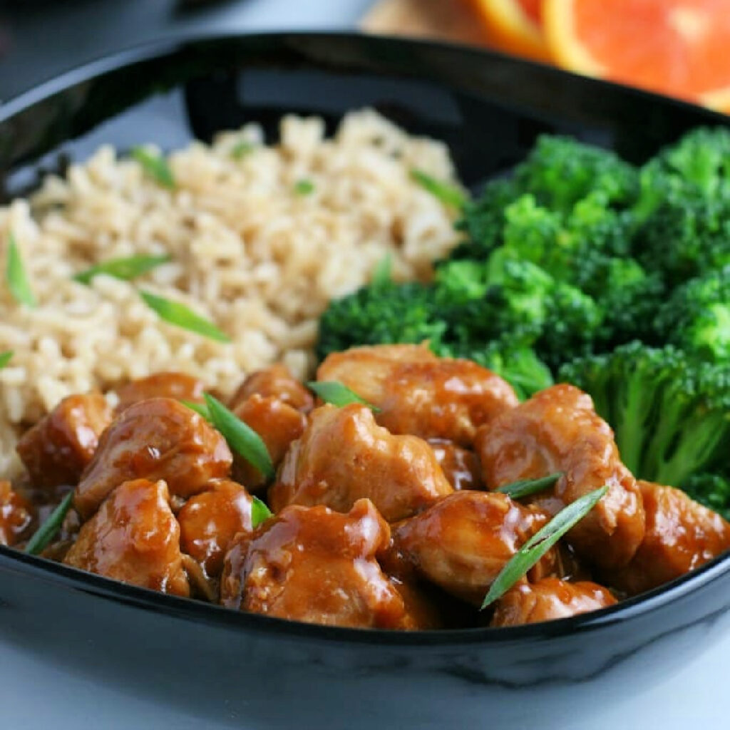 Close up of Orange Chicken in a bowl with rice and broccoli.