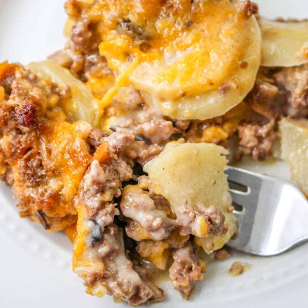 Close up of Hamburger and Potato Casserole on a white plate with a fork.