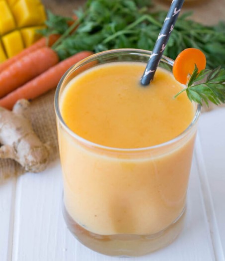 Mango, Carrot & Ginger Smoothie in a small glass with a straw.