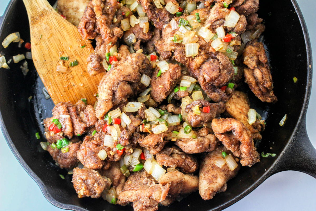 Salt and Pepper Chicken Stir Fry in a skillet with a wooden spoon.