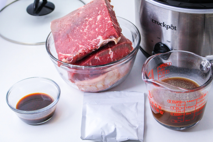 Slow Cooker Shredded Beef Ingredients on a counter top with a crockpot.