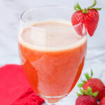 Glass with Iced Strawberry Tea garnished with a fresh strawberry.
