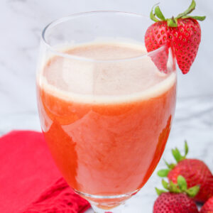 Glass with Iced Strawberry Tea garnished with a fresh strawberry.