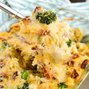 Serving spoon scooping Chicken Potato and Broccoli Casserole from a casserole dish.