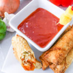 Pineapple Sweet and Sour Sauce in a bowl next to an egg roll.