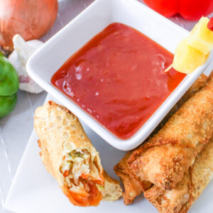 Pineapple Sweet and Sour Sauce in a bowl next to an egg roll.