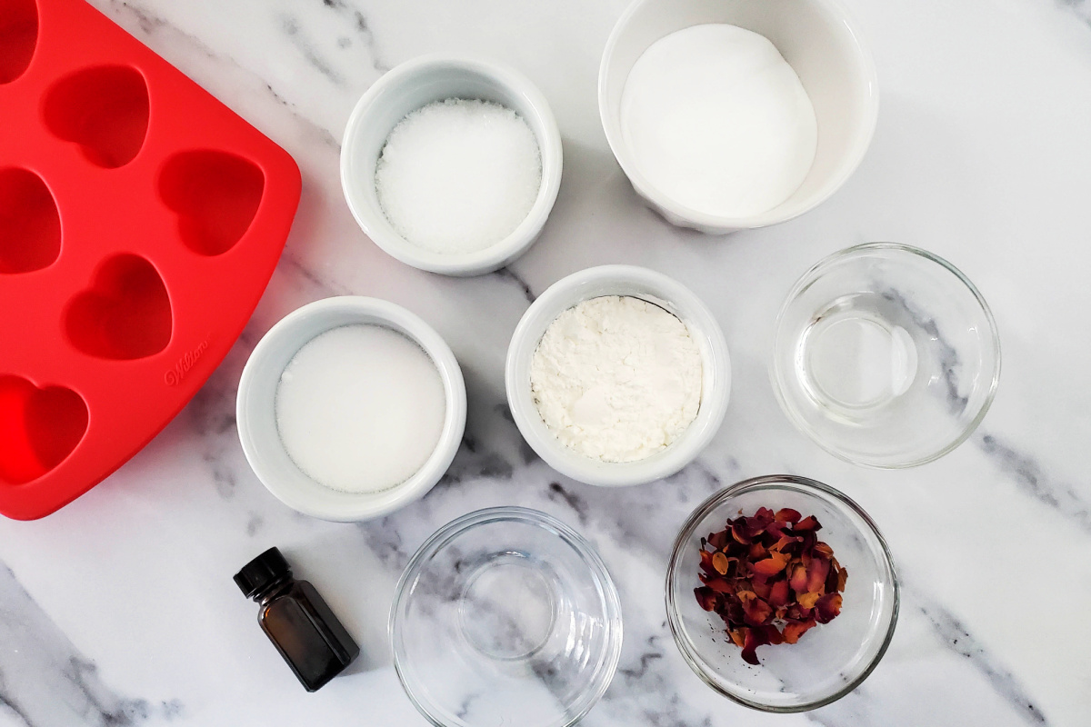 Ingredients and materials to make Rose Petal Bath Bomb on a countertop.
