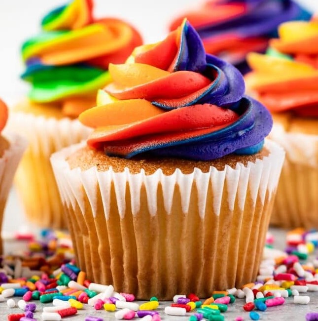 Rainbow Swirl Frosting cupcakes surrounded by sprinkles.