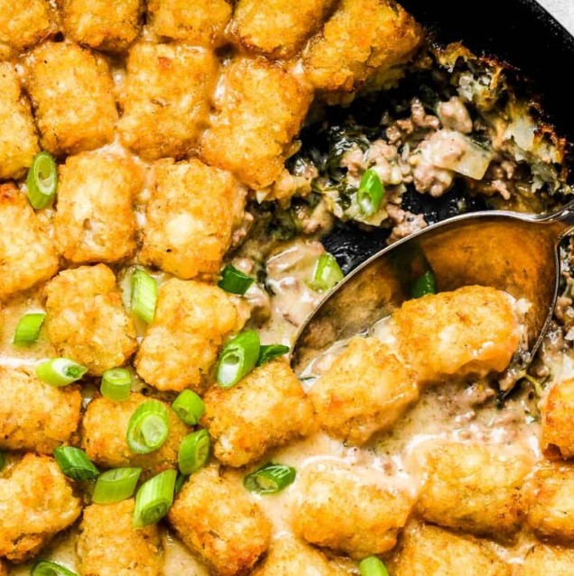Close up of a spoon in a Spinach Gruyere Tater Tot Hotdish.