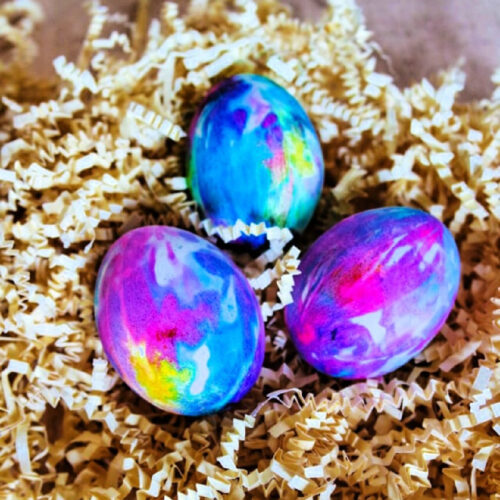 Three Tie Dye Easter Eggs nestled into craft paper.