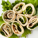 Turkey Pinwheels with greens on a platter.