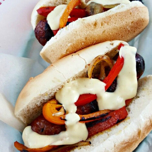 Grilled Brats with Beer Cheese Sauce, onions, and peppers.