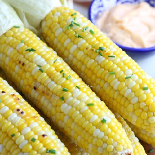 A pile of Grilled Corn on the Cob garnished with chives.