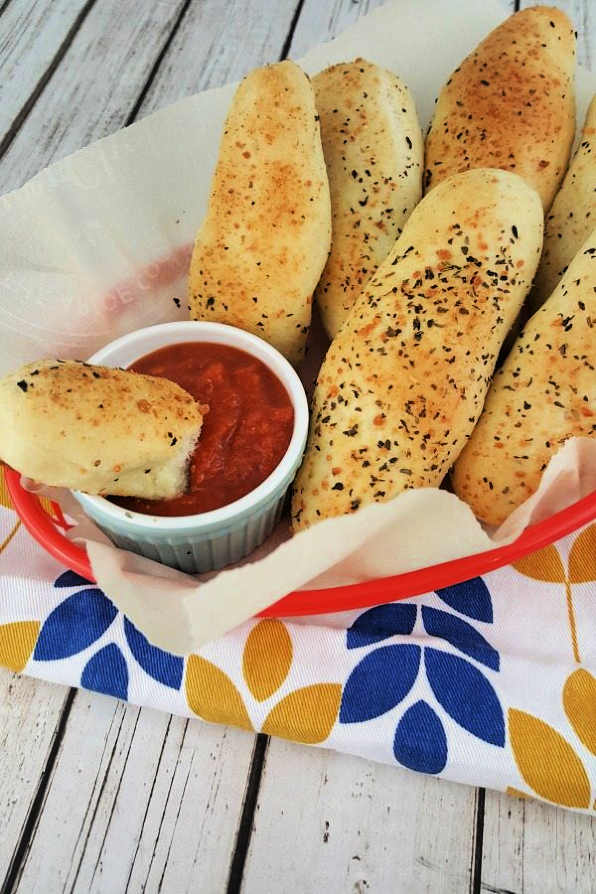 Italian breadsticks in a basket with marinara sauce.