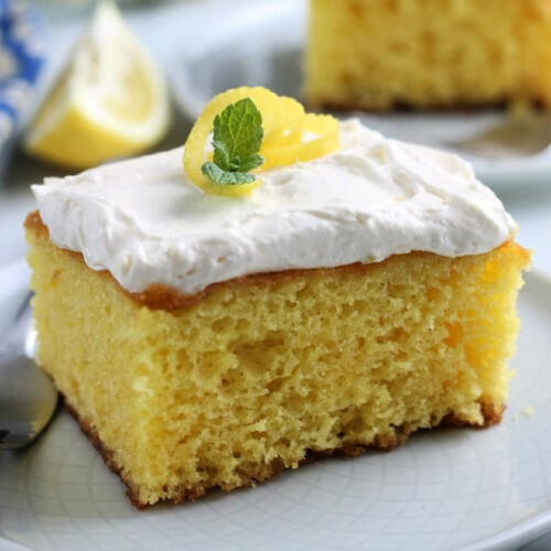 Lemon cake with whipped topping on a plate.