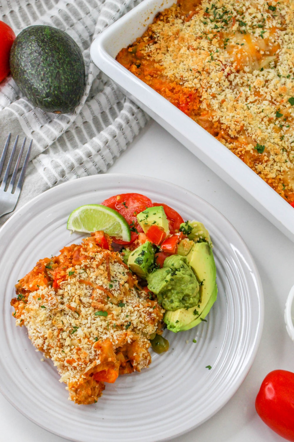 Chorizo and Potato Casserole on a plate with avocado and tomatoes.