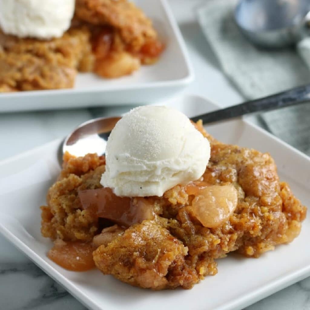 Crockpot Apple Cobbler with a big scoop of vanilla ice cream on top.