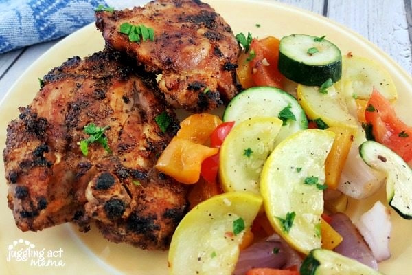Grilled Bone In Chicken Thighs on a plate with vegetables.