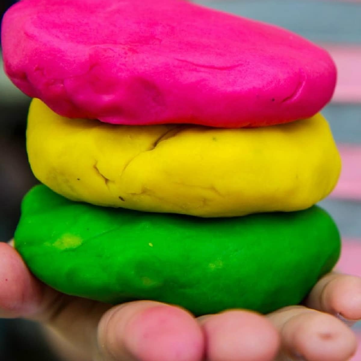 Three pieces of homemade playdough stacked up on a child's hand.
