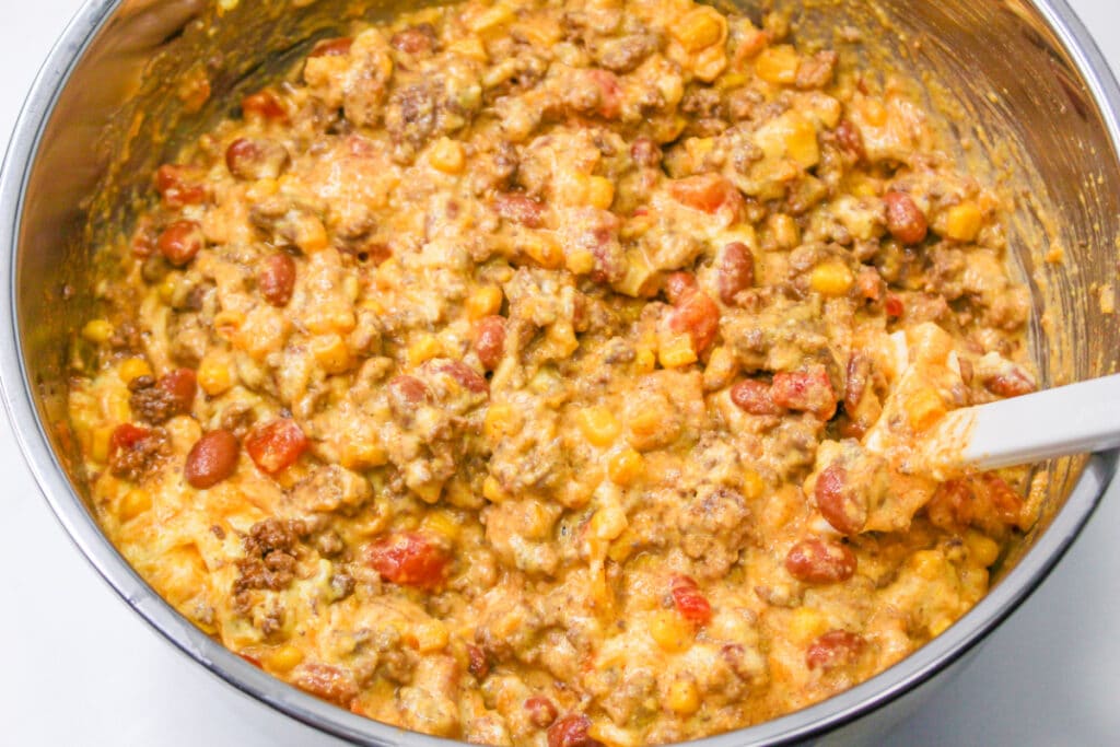 Beef and Bean Casserole mixture with cornbread batter in a bowl.
