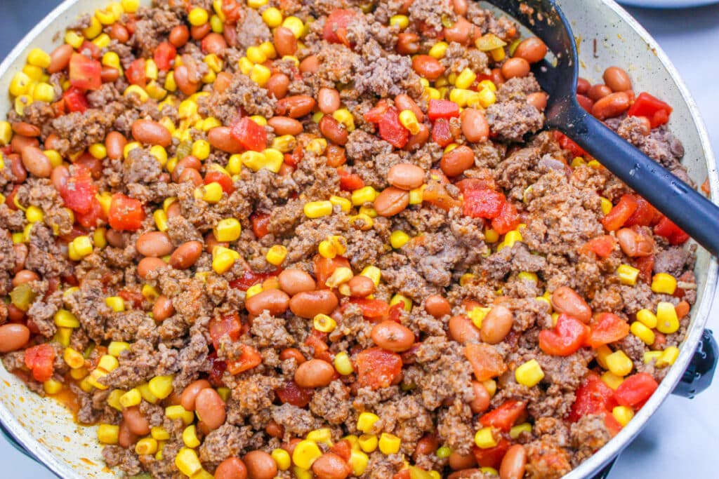 Ground beef, corn, beans and tomatoes in a skillet.