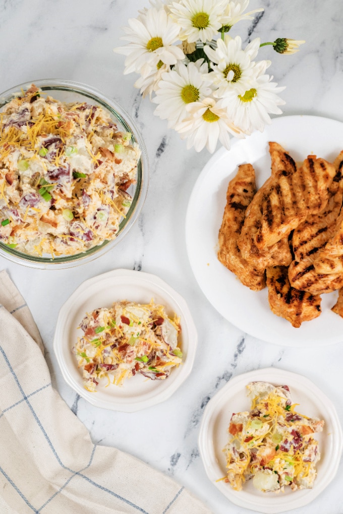 Loaded potato salad and chicken on plates.