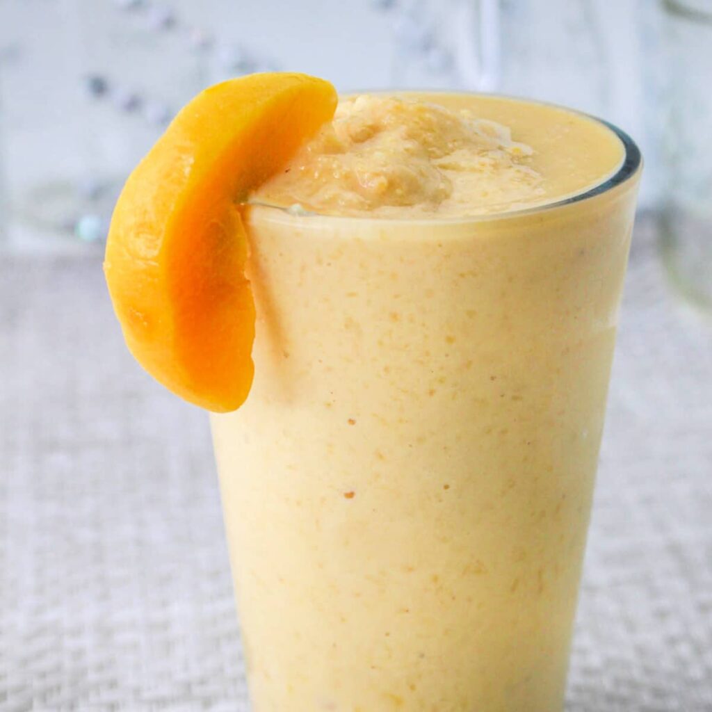 Simple Peach Smoothie Recipe - smoothie in a glass garnished with a fresh peach slice.