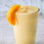 Simple Peach Smoothie Recipe - smoothie in a glass garnished with a fresh peach slice.