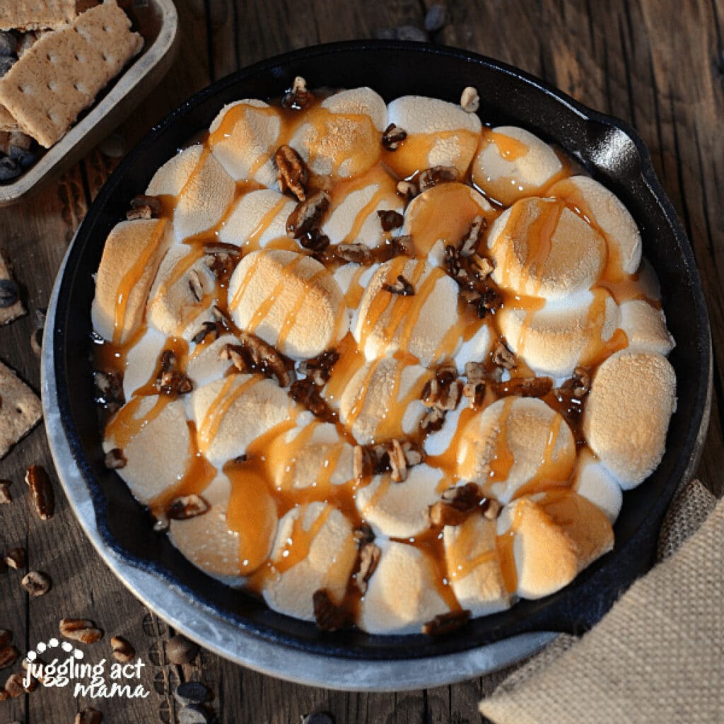 Marshmallows with chocolate, caramel, and pecans in a cast iron skillet.