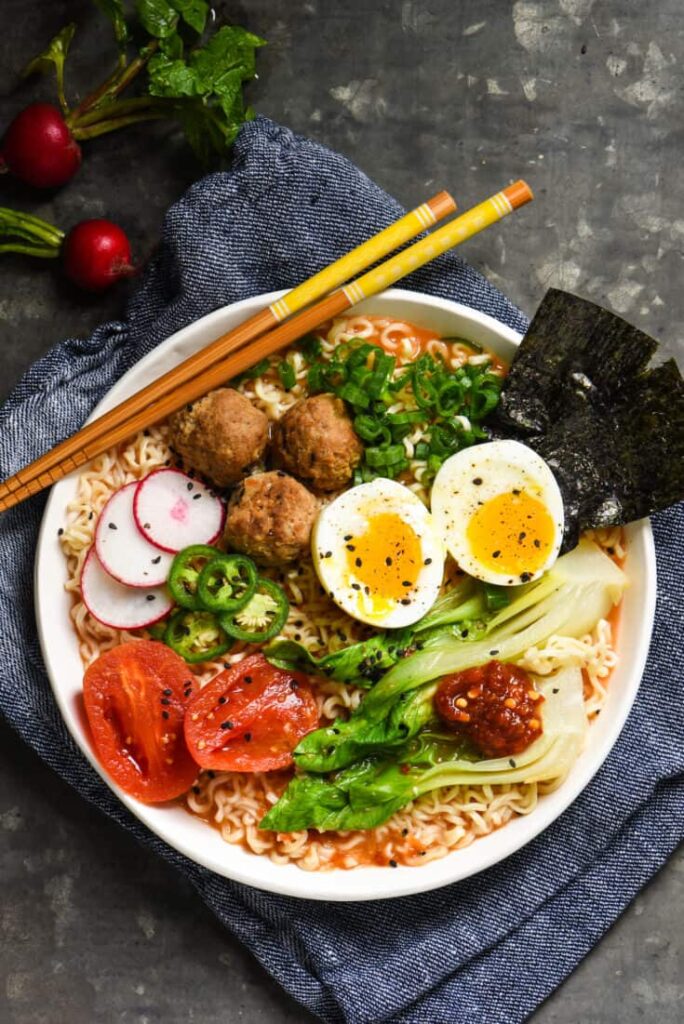 Recipes Using Meatballs: Tomato Ramen Noodles with Meatballs from Foxes Loves Lemons in a bowl with chop sticks.