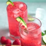 Raspberry Mojitos in tall glasses garnished with limes.
