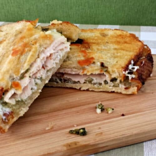 Sliced turkey pesto panini on a cutting board.