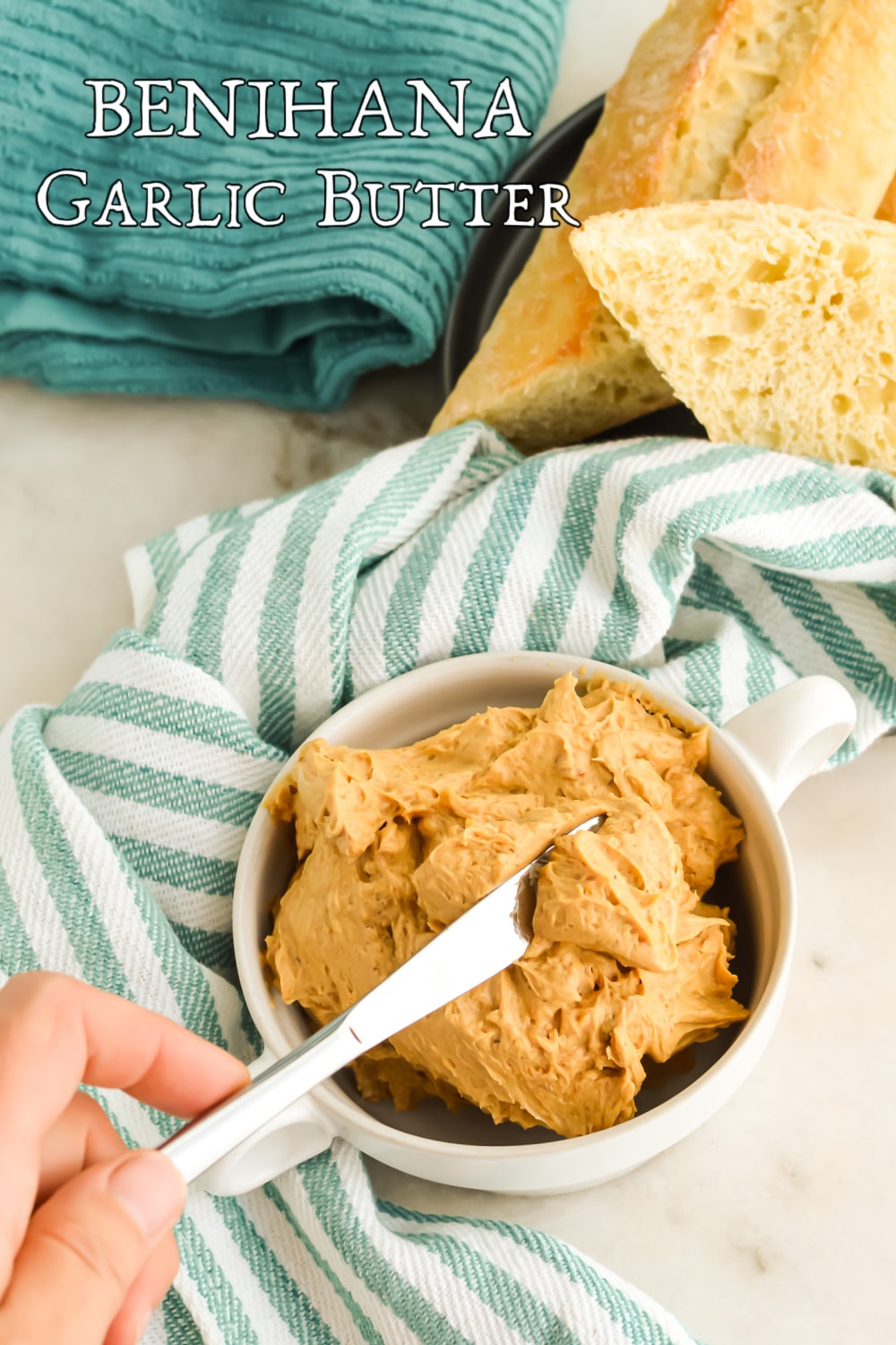 Woman's hand with a butter knife in a bowl of garlic compound butter with text overlay.